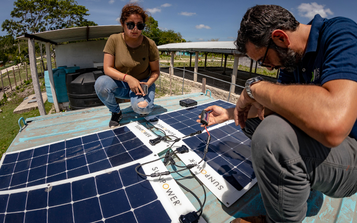 Alex Hatoum (rechts), Managing Director van IHS, en een collega installeren flexibele zonnepanelen op het dak van een nieuw WARP-systeem.